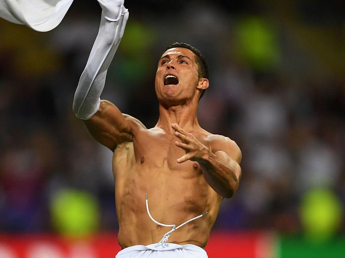 MILAN, ITALY - MAY 28:  Cristiano Ronaldo of Real Madrid takes off his shirt in celebration after scoring the winning penalty in the penalty shoot out during the UEFA Champions League Final match between Real Madrid and Club Atletico de Madrid at Stadio Giuseppe Meazza on May 28, 2016 in Milan, Italy.  (Photo by Laurence Griffiths/Getty Images)