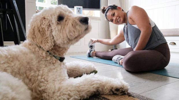 In this picture taken on March 26, 2020, Alison Yuen, 32, who is a Singapore national, takes a fitness class which was recorded by her personal trainer Kristen Handford, 33, as her dog sits nearby in her kitchen in Discovery Bay, on the outlying Lantau Island in Hong Kong. - More than 3.4 billion people have been called on or forced by authorities to stay at home, around 44 percent of the world population, according to a count based on an AFP database. Many are wondering how they can stay healthy during the weeks -- and possibly months -- of self-isolation that lie ahead. Hong Kongers, who live in some of the world's smallest apartments, say it can be done. (Photo by Anthony WALLACE / AFP) / TO GO WITH HongKong-health-virus-fitness,FOCUS by Jerome TAYLOR