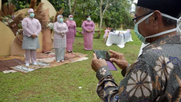 Tamu mengenakan masker saat menghadiri akad nikah pasangan suami-isteri Bayu Amde Winata dan Mike Agnesia yang berlangsung saat tanggap darurat COVID-19 di Kota Pekanbaru, Riau, Sabtu (4/4/2020). Pemerintah Indonesia mengimbau warga yang menikah untuk tidak mengumpulkan orang banyak, menyediakan masker dan pembersih tangan dan lokasinya di tempat terbuka serta menjaga pembatasan jarak fisik, agar tidak mempercepat penyebaran virus Corona. ANTARA FOTO/FB Anggoro/wsj.