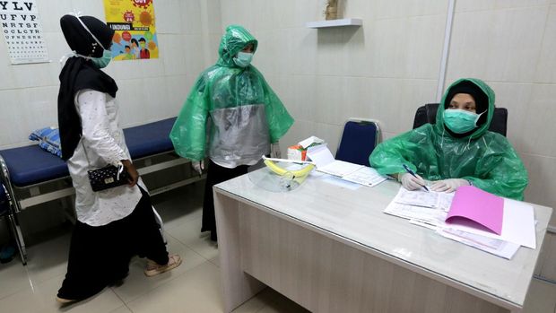 Petugas medis Puskesmas Ulee Kareng memakai jas hujan plastik sebagai alat pelindung diri (APD) saat melayani pasien di Banda Aceh, Aceh, Rabu (8/4/2020). Petugas medis di tingkat puskesmas menggunakan jas hujan karena keterbatasan APD yang sesuai standar guna menghindari penularan virus Corona (COVID-19). ANTARA FOTO / Irwansyah Putra/foc.