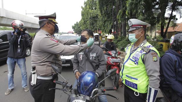 Polisi memberikan masker kepada pengendara sepeda motor saat penerapan Pembatasan Sosial Berskala Besar (PSBB) di Jalan H. Juanda, Lebak Bulus, Jakarta, Jumat (10/4/2020). Kegiatan pelaksanaan pengawasan PSBB itu dilakukan untuk mengingatkan warga memakai masker dan aturan penumpang dalam satu kendaraan. ANTARA FOTO/Reno Esnir/pras.