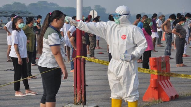 Petugas medis Gugus Tugas Percepatan Penanganan COVID-19 Sumut memeriksa suhu tubuh seorang Tenaga Kerja Indonesia (TKI) asal Malaysia ketika akan mengikuti senam dan berjemur di bawah sinar matahari saat menjalani karantina di Pangkalan Udara Militer (Lanud) Soewondo Medan, Sumatera Utara, Sabtu (11/4/2020). Sebanyak 513 TKI yang berasal dari berbagai daerah di Sumut dan sekitarnya yang menjalani proses karantina COVID-19 sementara tersebut saat ini kondisi kesehatannya baik dan tidak ada menunjukan gejala infeksi seperti demam, batuk dan sesak nafas. ANTARA FOTO/Septianda Perdana/hp.