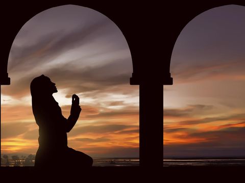 Silhoutte of muslim woman praying during fasting holy month of ramadan