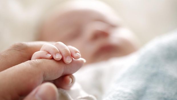 Sleeping baby clenches his parent's fingers; Soft focus and blurry