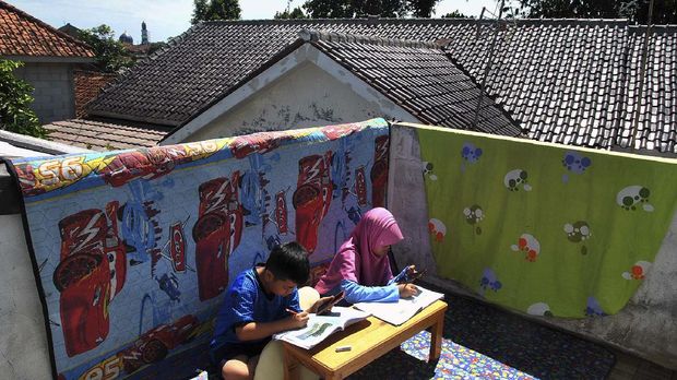 Siswa SD mengerjakan tugas sekolah menggunakan aplikasi daring dari gawai sambil berjemur sinar matahari pagi di rumahnya di Laladon Gede, Desa Laladon, Ciomas, Kabupaten Bogor, Jawa Barat, Selasa (31/3/2020). Gubernur Jawa Barat Ridwan Kamil memperpanjang masa belajar di rumah bagi siswa sekolah SD, SMP, SMA dan SMK atau setara di wilayah Jawa Barat selama dua minggu sampai dengan 14 April 2020 dalam rangka pencegahan penyebaran virus Corona (COVID-19). ANTARA FOTO/Arif Firmansyah/wsj.