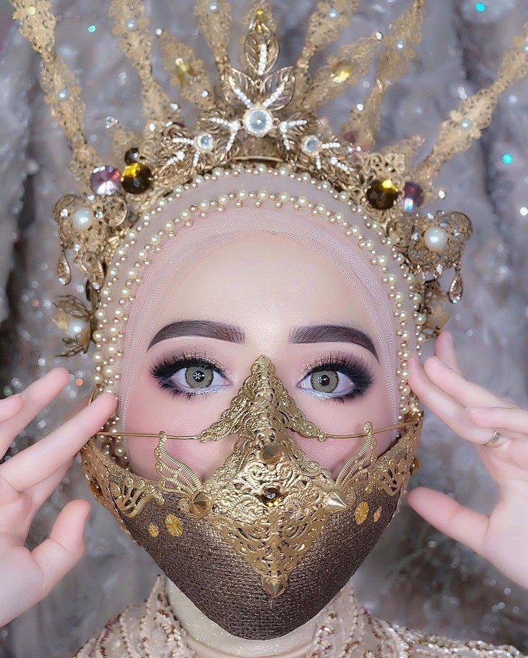 Pengantin yang menikah di tengah virus Corona ini juga bergaya memakai wedding fashion mask dari makeup artist @iis_yunerli86. Siger berbentuk masker ini terlihat unik saat digunakan oleh pengantin. Menurut kamu bagaimana? Foto: instagram @ieramakeup_nd_boutique