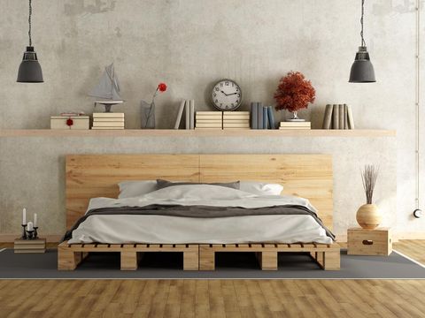 Patterned pouf and basket in bright bedroom interior with lamps, plants and poster next to bed. Real photo