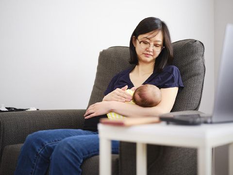 A Japanese mother breastfeeding her baby girl in a home nursery.