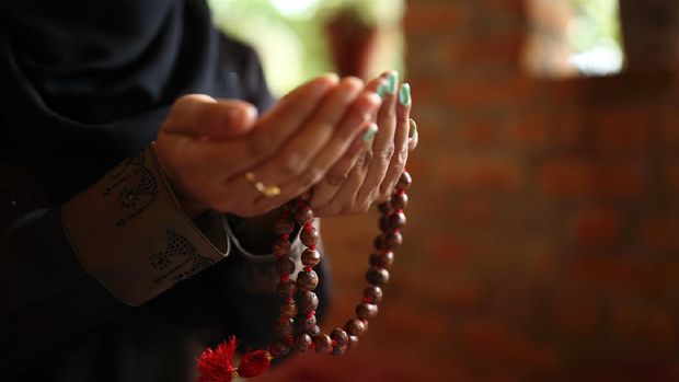 Close-up shot of a Muslim woman's hands holding rosary.