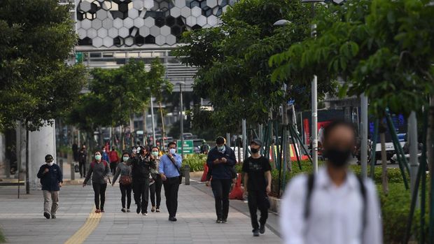 Sejumlah pekerja berjalan usai bekerja dengan latar belakang gedung perkantoran di Jl Jenderal Sudirman, Jakarta, Kamis (16/4/2020). Pemprov DKI Jakarta akan memberikan saksi berupa mencabut perizinan kepada perusahaan yang tetap beroperasi di masa Pembatasan Sosial Berskala Besar (PSBB) kecuali delapan sektor yang memang diizinkan. ANTARA FOTO/Akbar Nugroho Gumay/aww.