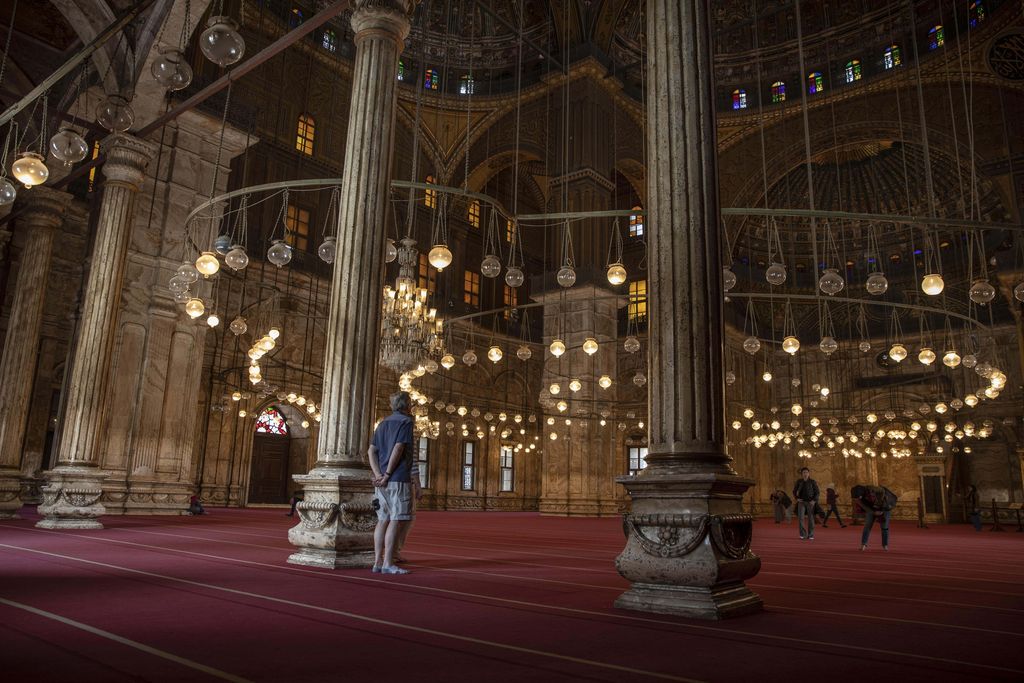 In this March 18, 2020 photo, an American tourist looks at the great Mosque of Muhammad Ali Pasha at the Citadel complex, in Cairo, Egypt. Like many other places in the world, the ripples of the worldwide coronavirus pandemic could end up drowning the vulnerable in Egypt. The partial lockdown threatens the livelihoods for many of Egypt's 100 million population, one of three of whom were already living in poverty, according to government figures. (AP Photo/Nariman El-Mofty)