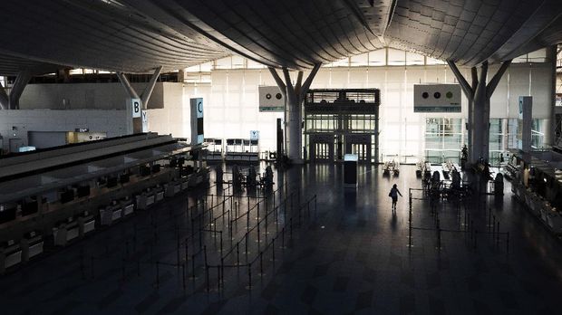 Sunyi Bandara Di Tokyo A woman walks through the empty ticketing area at Haneda International Airport in Tokyo, Friday, April 3, 2020. (AP Photo/Jae C. Hong)