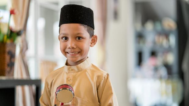 Young boy wearing traditional clothes looking excited in anticipation of the Islamic celebration of Hari Raya Aidilfitri (Eid al-Fitr). Kuala Lumpur, Malaysia. May 2018