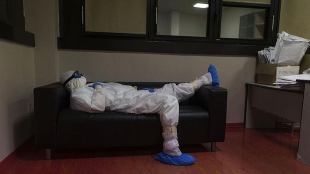 Doctor Giovanni Passeri relaxes in the doctor's lounge after completing a routine round of medical examinations during a night shift in his ward in the COVID-19 section of the Maggiore Hospital in Parma, northern Italy, Wednesday, April 8, 2020. Most of the times he is on a night shift the couch is the best Passeri can get to stretch out. A cardboard box at right holds envelopes with the medical charts of discharged patients. (AP Photo/Domenico Stinellis)
