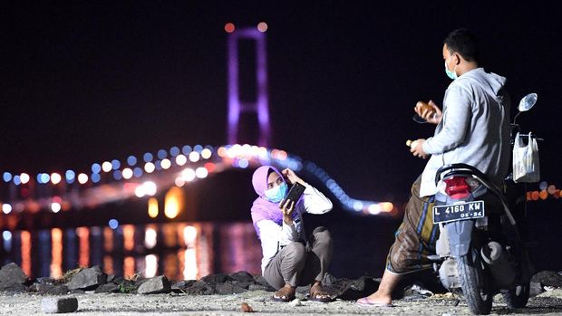 SUASANA KAWASAN JEMBATAN SURAMADU SAAT PANDEMI COVID-19 Sejumlah warga menikmati senja di pantai sisi timur Jembatan Suramadu di Surabaya, Jawa Timur, Jumat (17/4/2020). Akibat pandemi virus Corona (COVID-19), suasana di kawasan itu sepi pengunjung. ANTARA FOTO/Zabur Karuru/wsj.