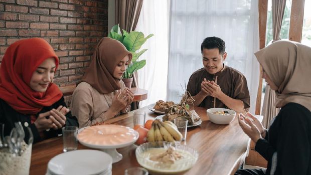asian muslim people praying before having their food in dining room together for break fasting