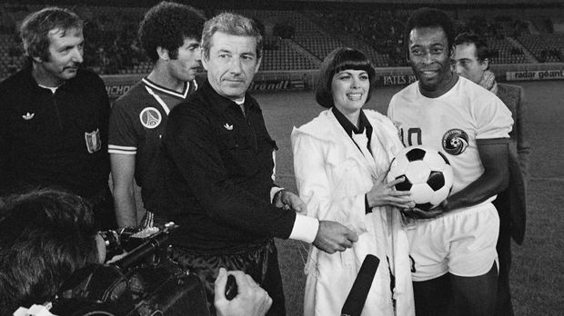 French singer Mireille Mathieu (C), designer Daniel Hechter (Rear R) stand with Brazilian player PelÈ and Algerian forward Mustapha Dahleb (2ndL) after making a ceremonial kick off during a match between the New-York Cosmos team and Paris Saint-Germain at the Parc des Princes on September 14, 1976. (Photo by - / AFP)