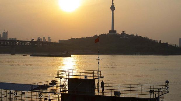 In this April 8, 2020, photo, a man looks across the Yangtze River as the sun sets in Wuhan in central China's Hubei province. The reopening of ferry service on the Yangtze River, the heart of life in Wuhan for more than 20 centuries, was an important symbolic step in official efforts to get business and daily life in this central Chinese city of 11 million people back to normal after a 76-day quarantine ended in the city at the center of the coronavirus pandemic. (AP Photo/Ng Han Guan)
