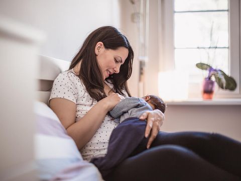 Young mother breastfeeding her baby boy in the bedroom. Belgrade, Serbia