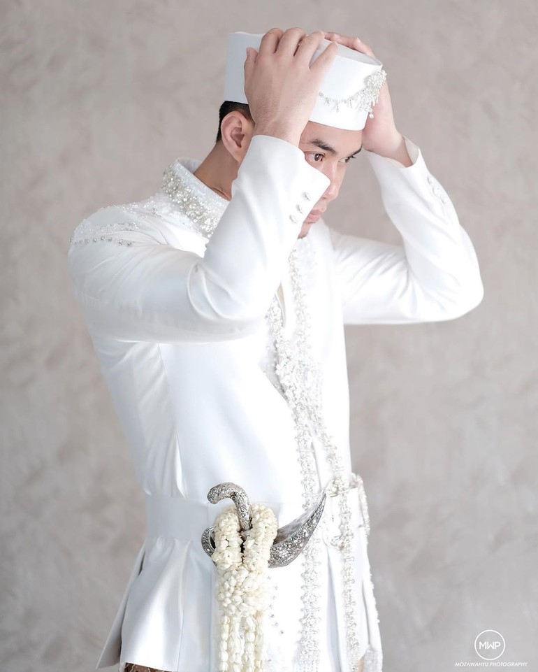 Sementara Sirajuddin tampil gagah dengan beskap putih bertabur kristal yang juga datang dari label bridal Ivan Gunawan, Love Ivan Gunawan. Bros pada peci dan kalung yang disematkan pada beskap pun dirancang khusus oleh Rinaldy A. Yunardi. Foto: Instagram/@mozawahyu, @ivan_gunawan, @anpasuha_official