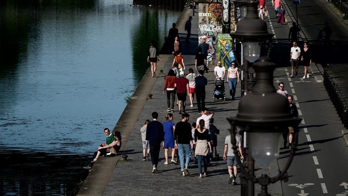 People walk along the Ourc canal during a sunny Sunday in Paris on April 26, 2020 despite a strict lockdown to stop the spread of the Covid-19 pandemic caused by the novel coronavirus. (Photo by Philippe LOPEZ / AFP)