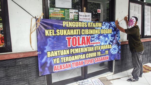 Warga beserta pengurus RT dan RW membawa poster tuntutan serta menggunakan toppeng saat melakukan aksi unjuk rasa di Kantor Kelurahan Sukahati, Cibinong, Bogor, Jawa Barat, Senin (27/4/2020). Aksi tersebut menuntut adanya ketidak sinkronan data penerima bantuan sosial warga terdampak COVID-19, serta bantuan tersebut dinilai tidak tepat sasaran. ANTARA FOTO/Yulius Satria Wijaya/hp..