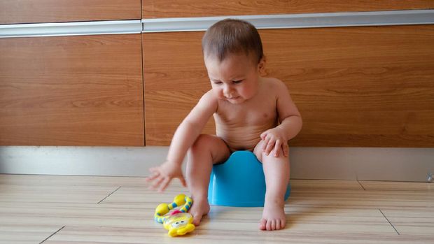 cute six months old baby boy siting on the blue potty early development concept