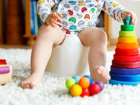 cute six months old baby boy siting on the blue potty early development concept