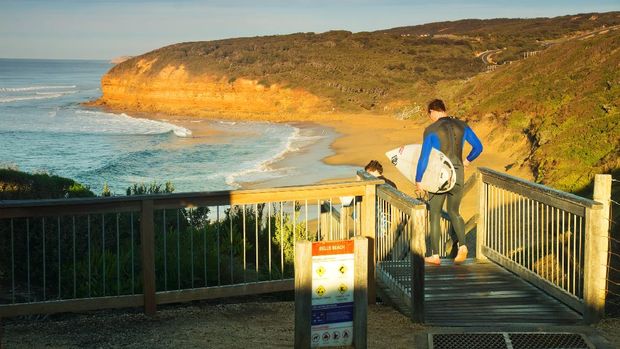 Bells Beach, Australia - May 13, 2014: Surfers head down a staircase leading to Bells Beach at sunrise. A renowned surf beach, the Rip Curl Pro is held here every Easter.
