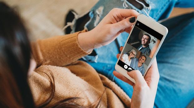 Young woman connecting with her family during quarantine. She's using a smartphone to call her family in Coronavirus COVID-19 time.