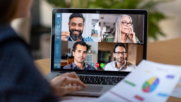 Back view of business woman talking to her colleagues about business plan in video conference. Multiethnic business team using laptop for a online meeting in video call. Group of businessmen and businesswomen smart working from home.