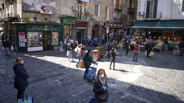 People line up to buy fruit and vegetables at a shop in Naples, Monday, April 27, 2020. Region Campania allowed cafes and pizzerias to reopen for delivery Monday, as Italy it is starting to ease its lockdown after a long precautionary closure due to the coronavirus outbreak. (AP Photo/Andrew Medichini)