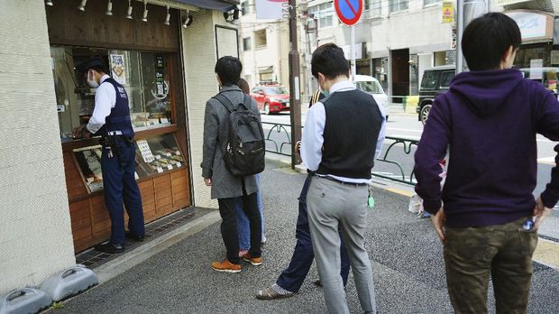 FILE - In this April 22, 2020, file photo, people wearing masks to protect themselves against the spread of the new coronavirus queue up to buy lunch at a shop in Tokyo. Under Japan's coronavirus state of emergency, people have been asked to stay home. Many are not. Some still have to commute to their jobs despite risks of infection, while others are dining out, picnicking in parks and crowding into grocery stores with scant regard for social distancing. (AP Photo/Eugene Hoshiko, File)