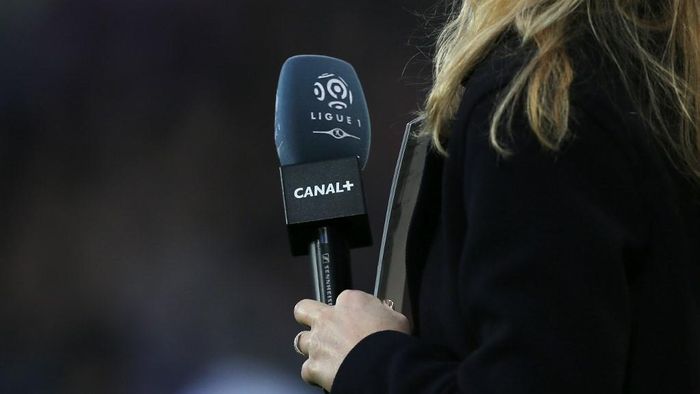 (FILES) In this file photograph taken on December 19, 2015, a journalist holds a microphone with the logo of French first football division Ligue 1 and Canal Plus television broadcaster before the French L1 football match between Caen (SM Caen) and Paris Saint-Germain (PSG) at The Michel dOrnano stadium, in Caen, north-western France. - The Professional Football League (LFP) and its broadcasters Canal+ and beIN Sports announced April 24, 2020, an agreement for the payment of TV rights for L1 and L2 matches already played, which they had refused to pay until then. (Photo by Charly TRIBALLEAU / AFP)