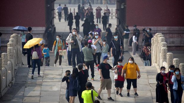 Visitors wearing face masks to protect against the new coronavirus walk through the Forbidden City in Beijing, Friday, May 1, 2020. The Forbidden City reopened beginning on Friday, China's May Day holiday, to limited visitors after being closed to the public for more than three months during the coronavirus outbreak. (AP Photo/Mark Schiefelbein)