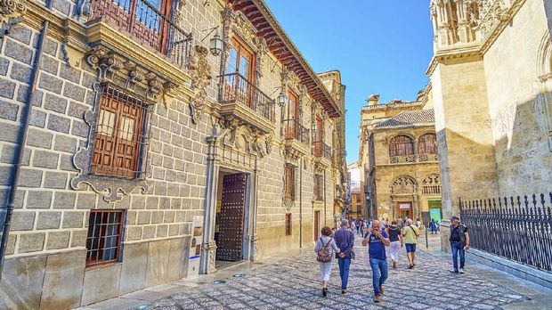 Madrasah of Granada Granada, Spain - September 25, 2019: Tourists walk in Calle Oficios (La Lonja square), lined with historic buildings of Capilla Real (Royal Chapel) and Palacio de la Madraza (Madrasah school)
