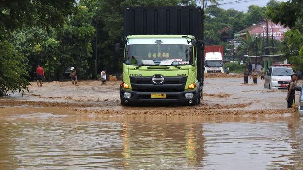 Warga memandu sopir truk melewati banjir di Jalan Cilegon-Merak, Grogol, Cilegon, Banten, Senin (4/5/2020).Banjir yang terjadi akibat tanggul Kali Ciore jebol setelah diguyur hujan sejak Minggu (3/5) malam itu mengakibatkan ratusan rumah dan jalan terendam air setinggi 40-110 centimeter. ANTARA FOTO/Asep Fathulrahman/pras.