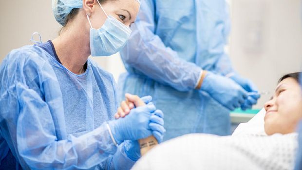 Team of doctors and nurses wear masks and gloves and prepare for surgery.