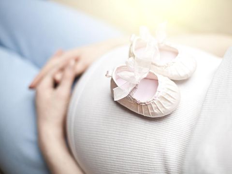 Baby shoes on the pregnant woman belly
