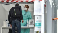 Seseorang melakukan pengecekan suhu tubuh jelang masuk ke J-Medical. Protokol keamanan masih ketat di markas Si Nyonya Tua. (Foto: MARCO BERTORELLO/AFP)