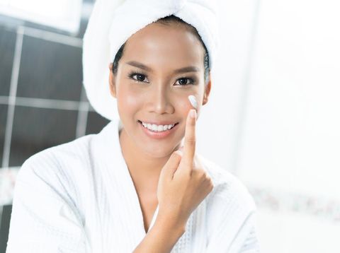 Asian women are applying cream and lotion to her face after bathing in the bathroom.