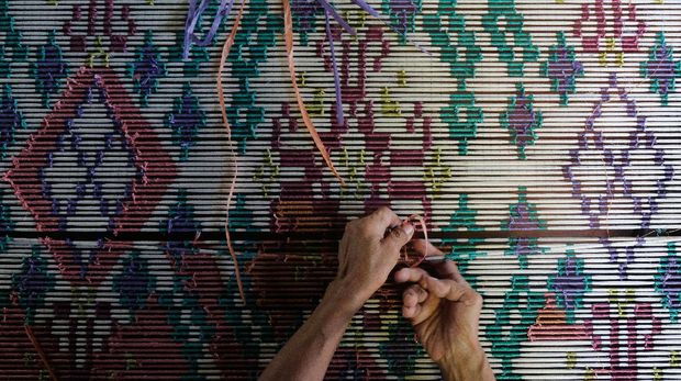 Perajin mengikat benang sesuai motif sebelum proses pewarnaan. ANTARA FOTO/Nyoman Hendra Wibowo