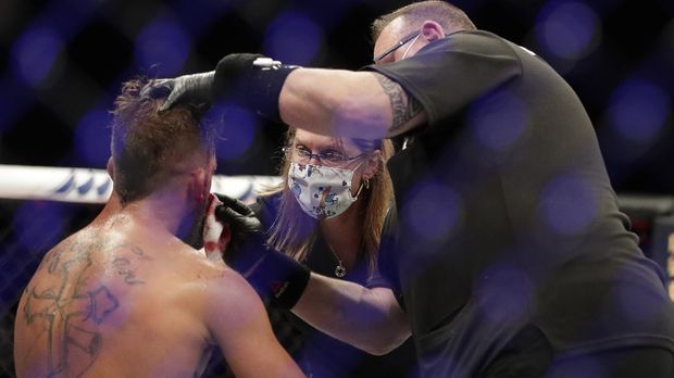 Para petugas medis melakukan perawatan terhadap petarung UFC dengan mengenakan masker. (