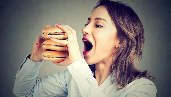 makan berlebihan Woman eating craving a tasty double burger