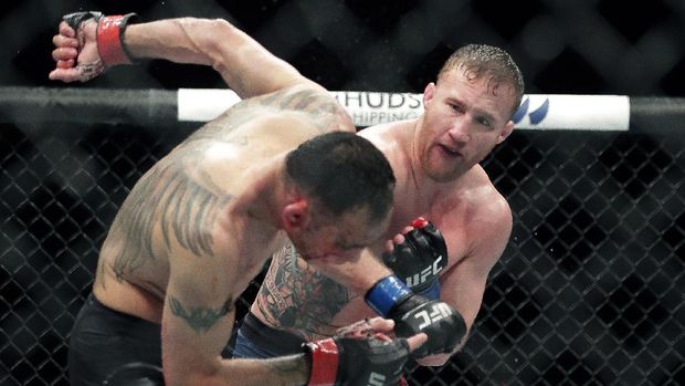 Tony Ferguson, left, falls backward after taking a punch from Justin Gaethje during a UFC 249 mixed martial arts bout, early Sunday, May 10, 2020, in Jacksonville, Fla. (AP Photo/John Raoux)