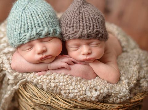 Seven week old fraternal, twin baby girls sleeping on a white flokati rug.