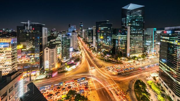 Aerial view of famous crowded Crossing at Downtown Gangnam Station at night with traffic and surrounding tall skyscrapers. New Voigtlander Helinar 10mm Ultra Wide Angle, Unique Perspective, 42MP shot from aerial perspective. Gangnam District, Seoul, South Korea