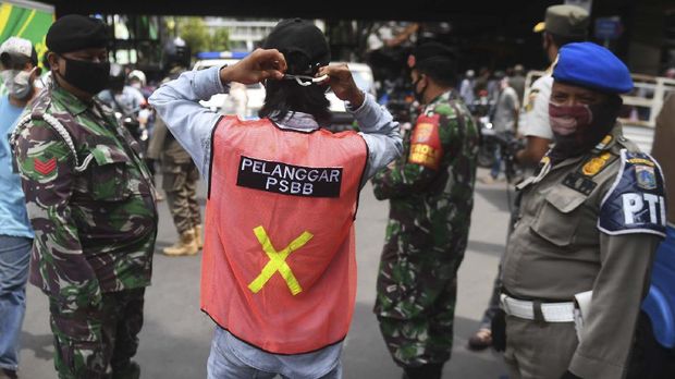 Seorang warga yang terjaring razia penindakan pelanggaran aturan Pembatasan Sosial Berskala Besar (PSBB) oleh Satpol PP menjalani hukuman dengan cara membersihkan sampah di Tanah Abang, Jakarta, Rabu (13/5/2020). Pemprov DKI Jakarta mulai memberlakukan sanksi sosial terhadap pelanggar PSBB yaitu dengan memakaikan rompi bertuliskan pelanggar PSBB saat mereka membersihkan fasilitas umum. ANTARA FOTO/Akbar Nugroho Gumay/aww.