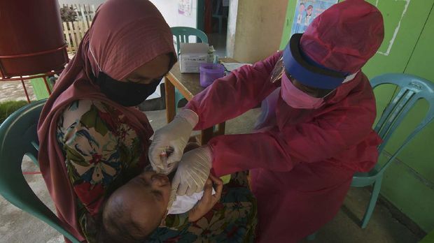 Petugas memberikan vaksin kepada salah satu anak saat imunisasi di salah satu posyandu di Palu, Sulawesi Tengah, Rabu (6/5/2020). Meski tengah dilanda pandemi COVID-19, pelaksanaan imunisasi yang bertujuan untuk menjaga kesehatan anak tersebut tetap berjalan, dengan menerapkan jaga jarak (physical distancing), dilaksanakan pada ruang terbuka serta wajib menggunakan masker. ANTARA FOTO/Mohamad Hamzah/aww.