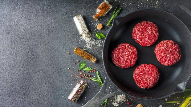 ilustrasi kornet goreng Raw minced meat beef burger cutlets. Cooking meat and burgers background with olive oil. herb, spices, black stone or concrete table, above, copy space